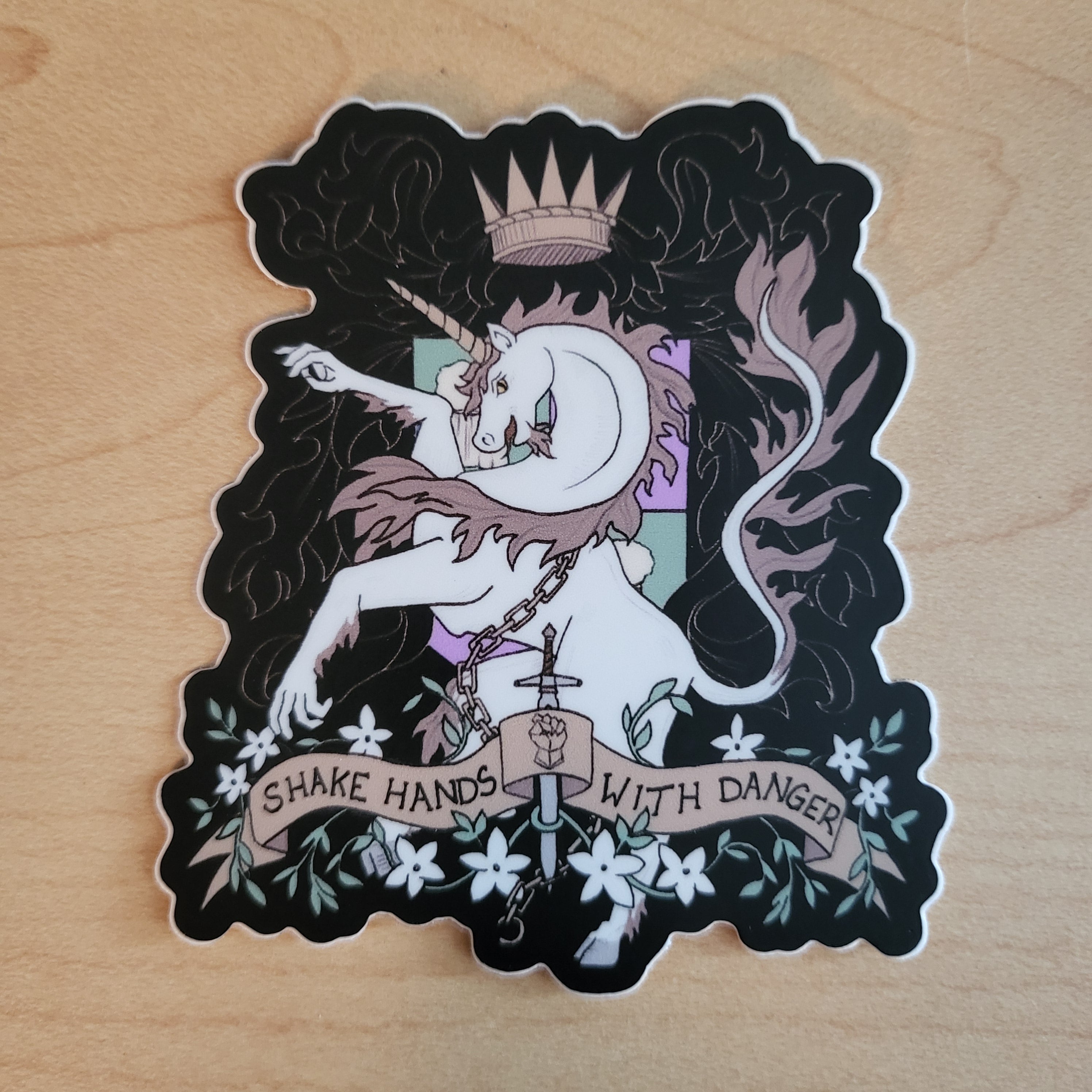 Sticker of a unicorn with hands done in a heraldry style, featuring the words Shake Hand with Danger on a banner across the bottom.