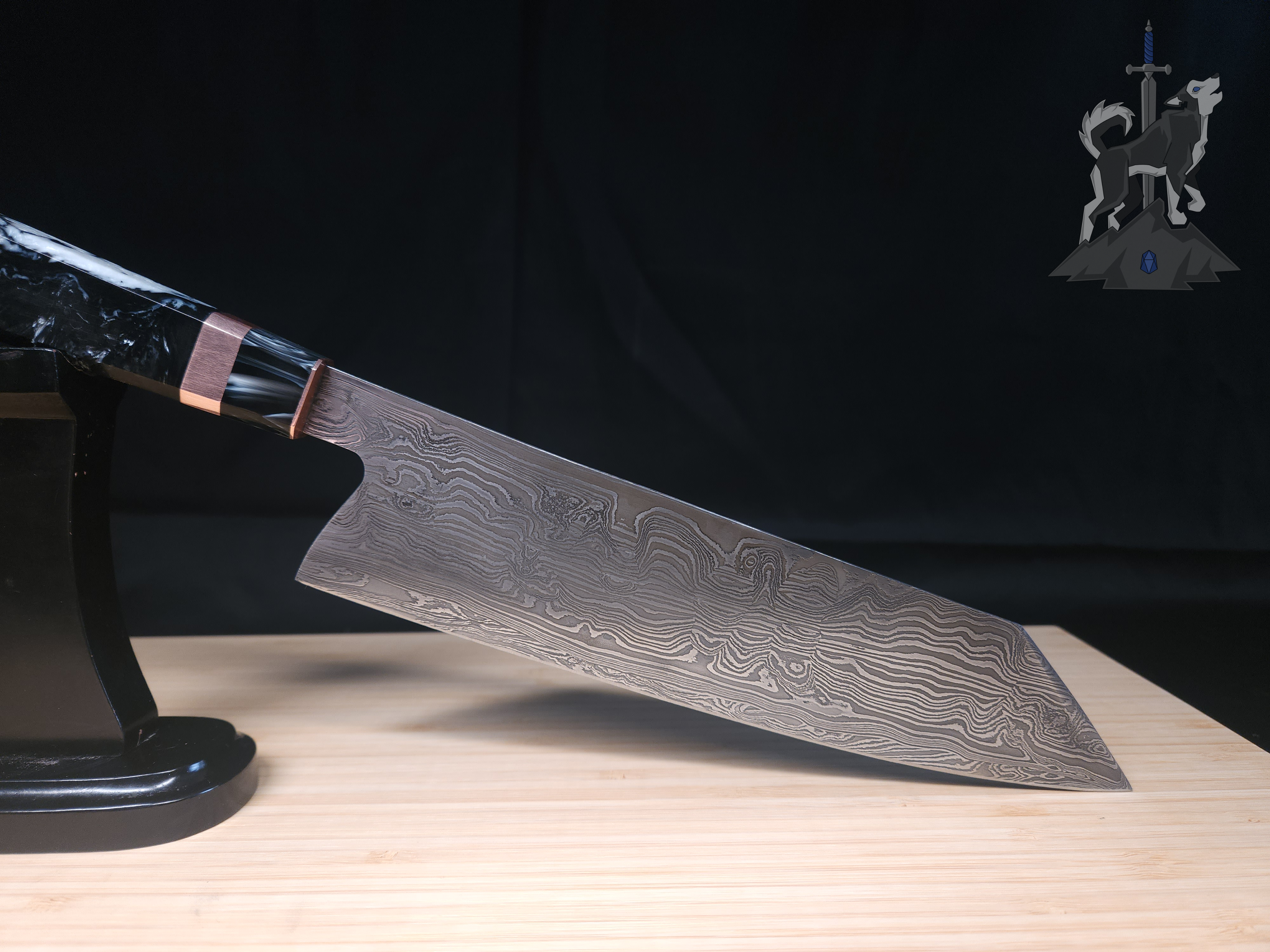 A Damascus chef's knife on a stand on a wooden cutting board with a black background