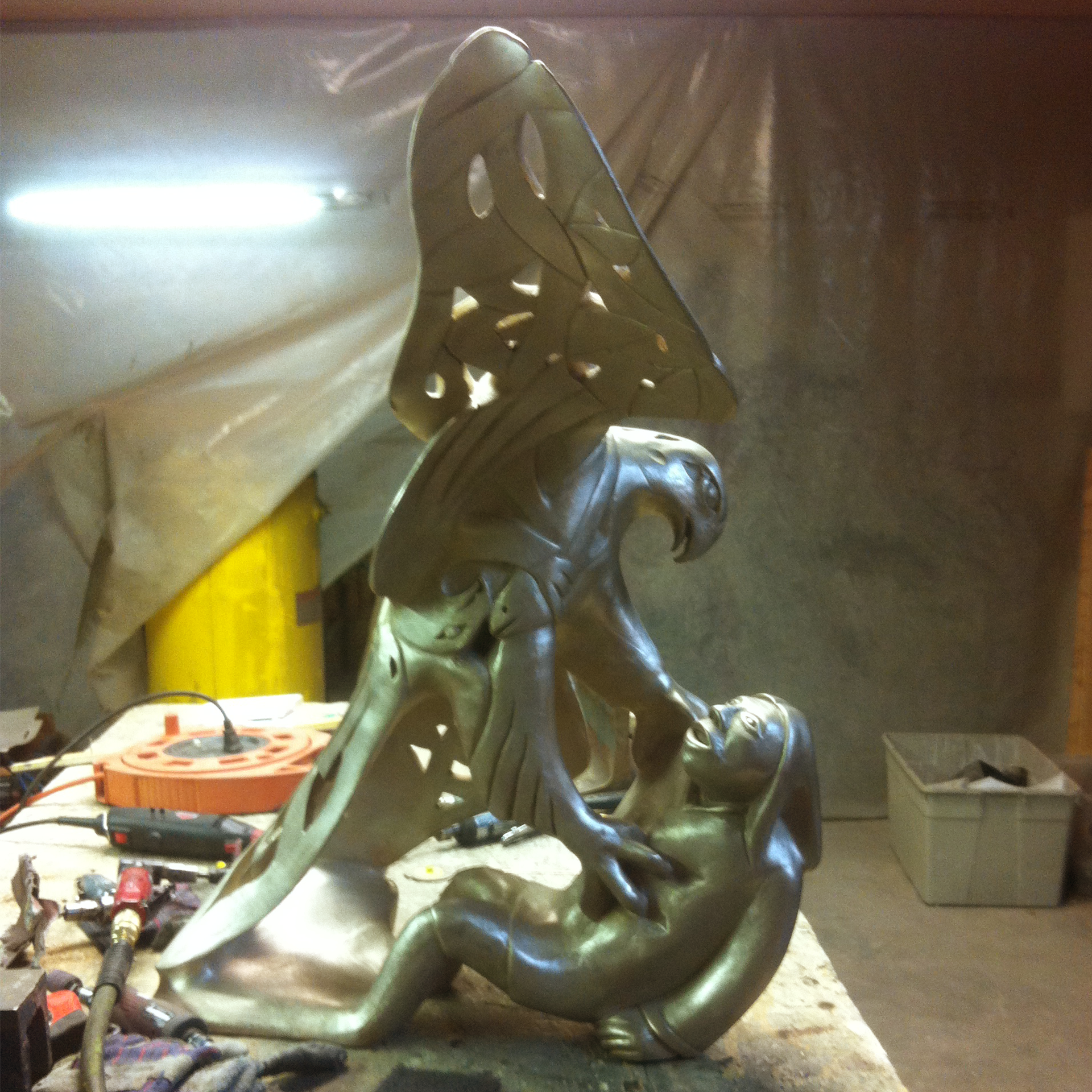 Bronze sculpture recreation of an eagle and a man in a workshop setting