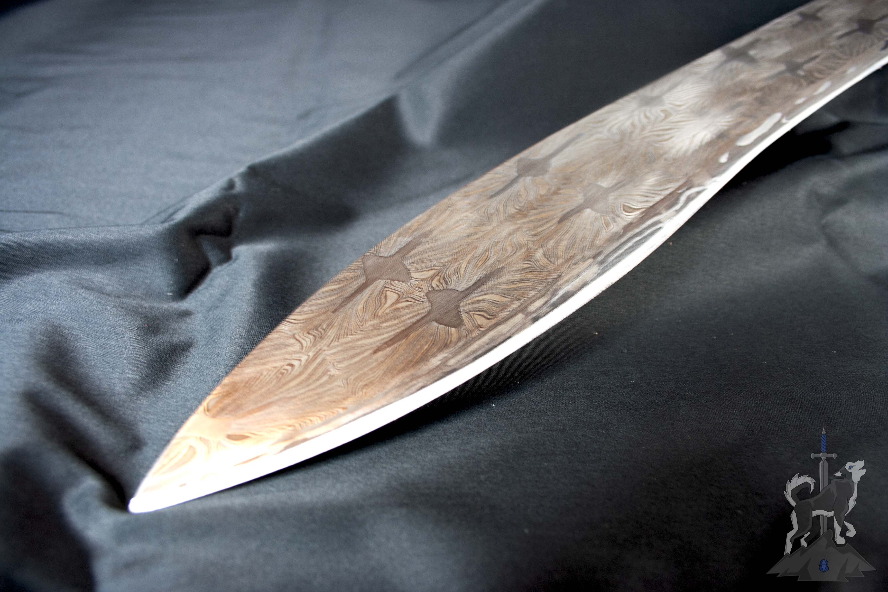 Close up of a Damascus kukri hybrid blade tip on a dark background