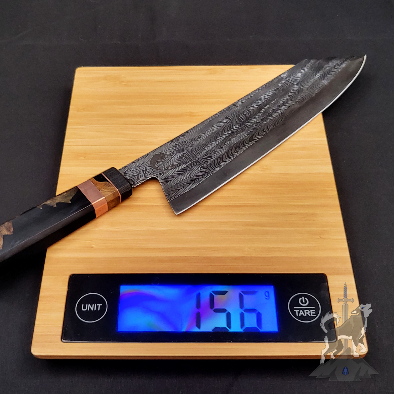 Chef's knife with a Damascus pattern on a digital kitchen scale displaying weight.