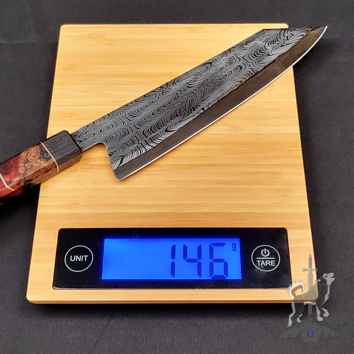Chef's knife with a Damascus pattern on a digital kitchen scale displaying weight.