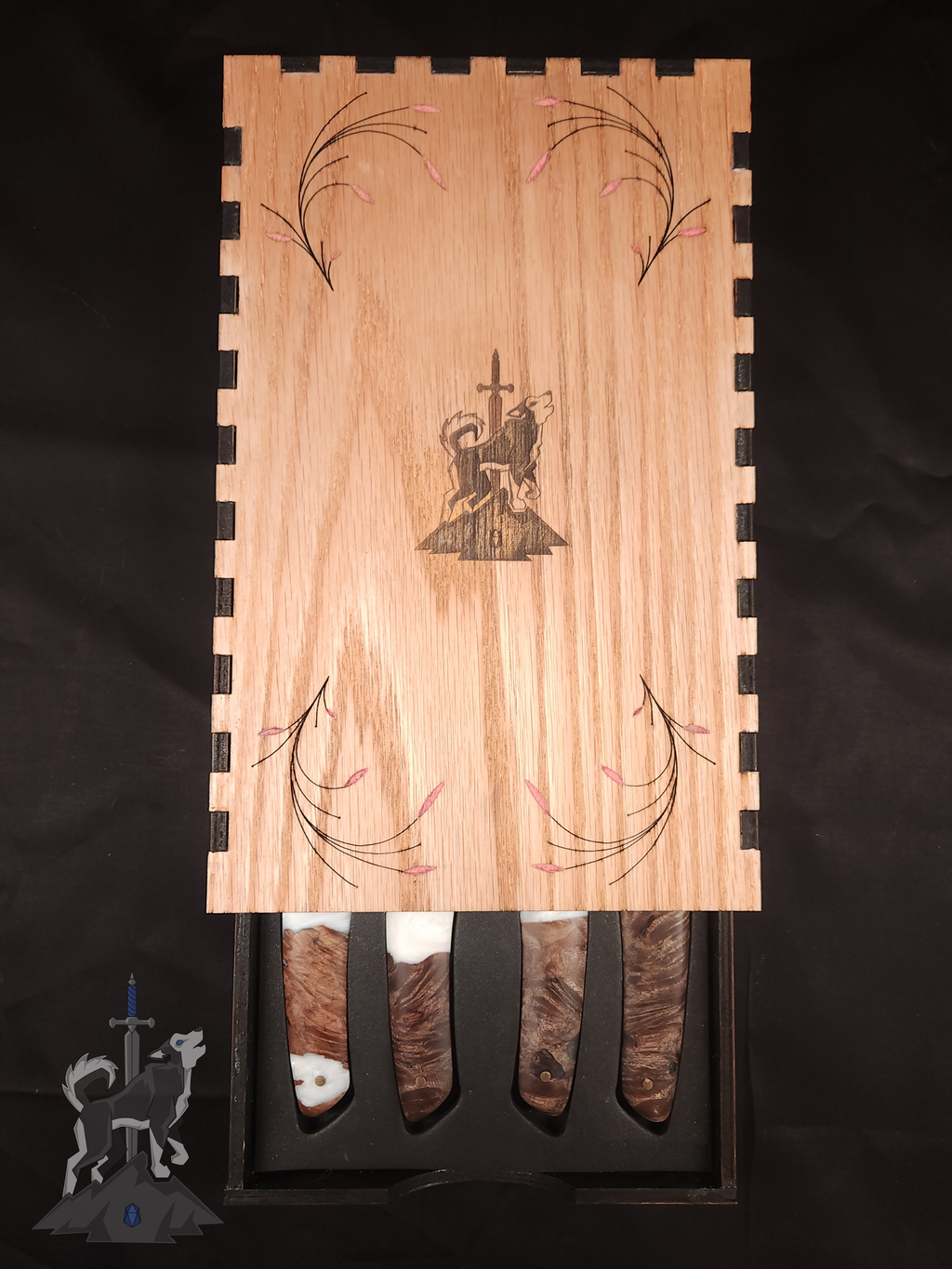 Four feather patterned Damascus steak knives with white and wooden handles seated in their wooden storage box on a dark background with only the ends of the handles visible
