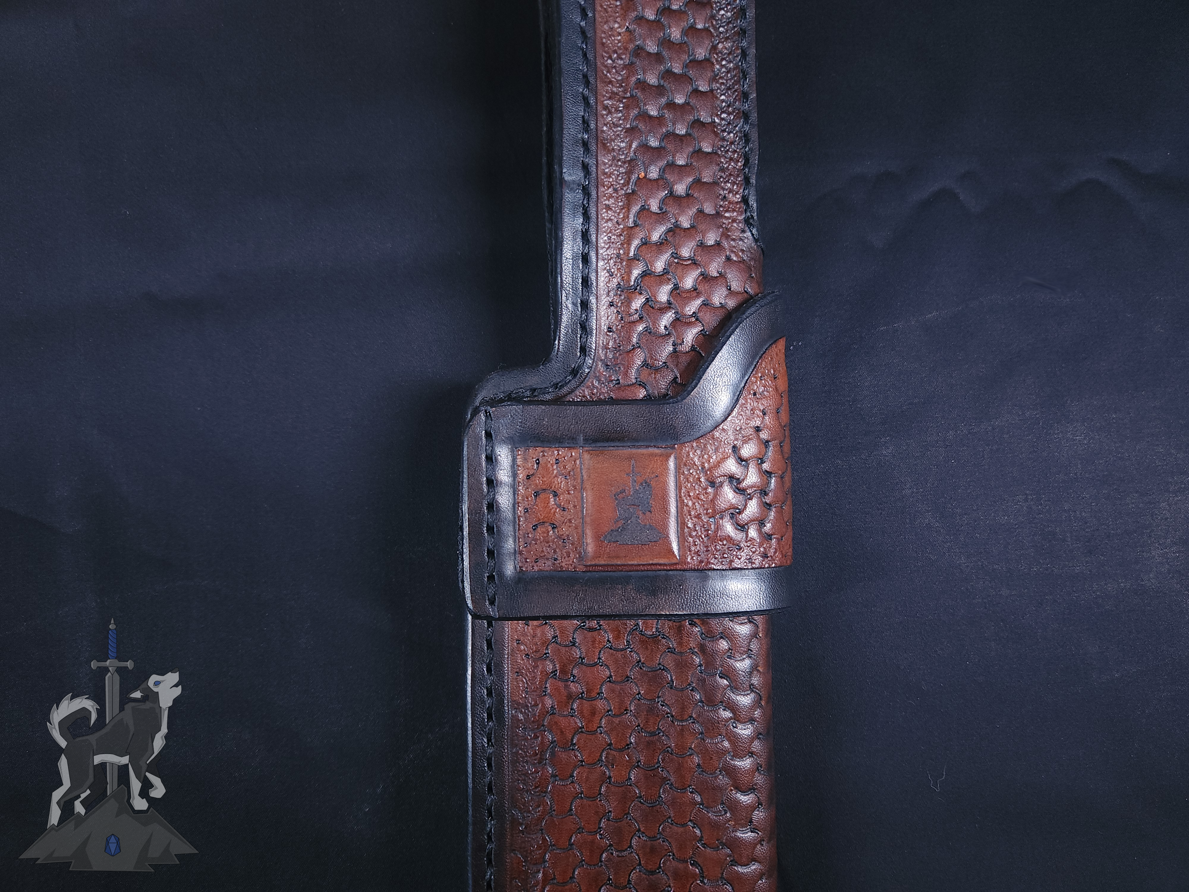 Detailed shot of the hand tooled leather sheath for the custom Damascus takedown bowie featuring a laser engraved Principle Forge logo