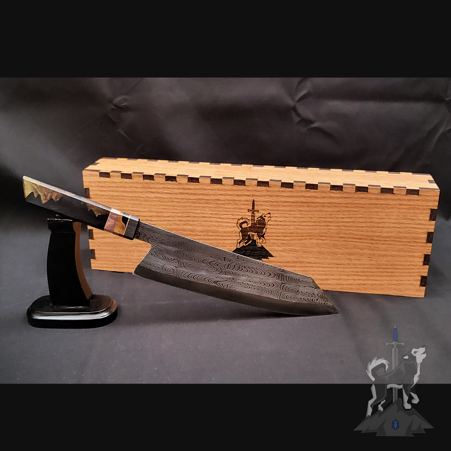 Chef knife with Damascus pattern on a stand next to a wooden box on a dark background