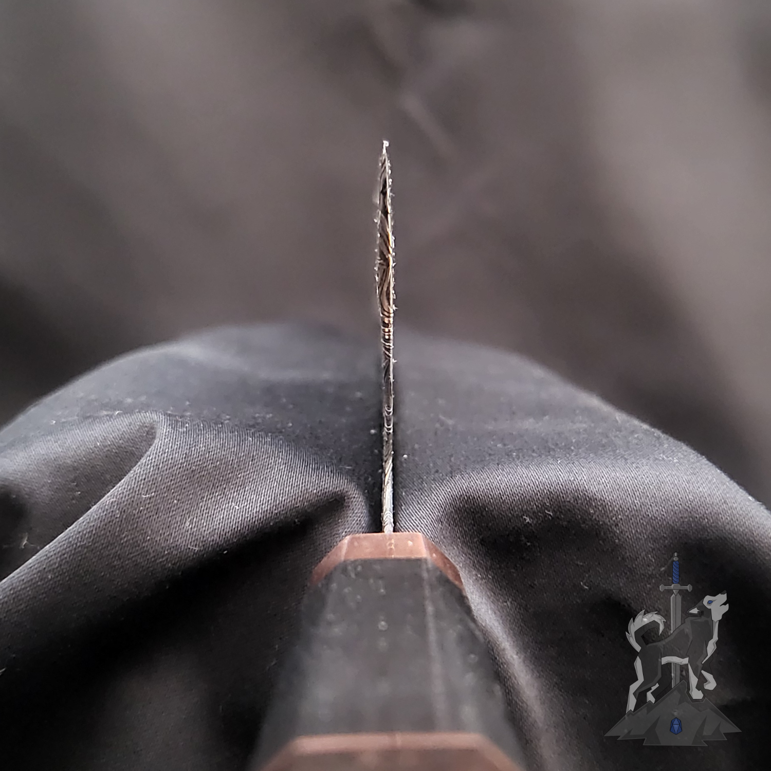 Close-up of a Damascus chef knife choil with a blurred black background.